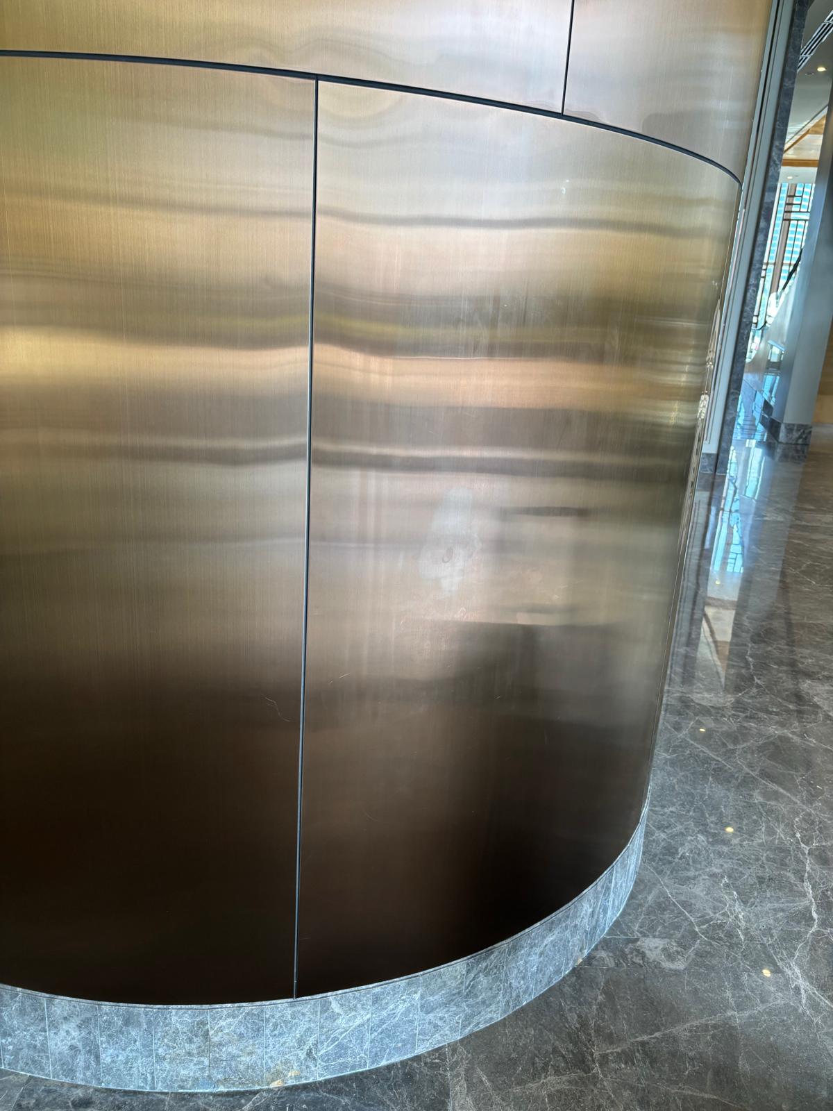 Brushed metal curved wall cladding in hotel lobby